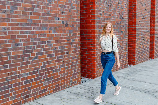 Beautiful young woman posing at the city street background. Girl relax in a sunny day. Travel and active life concept.