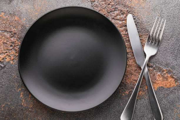 istock Empty black plate and cutlery on the table, top view. Food background 1284590056