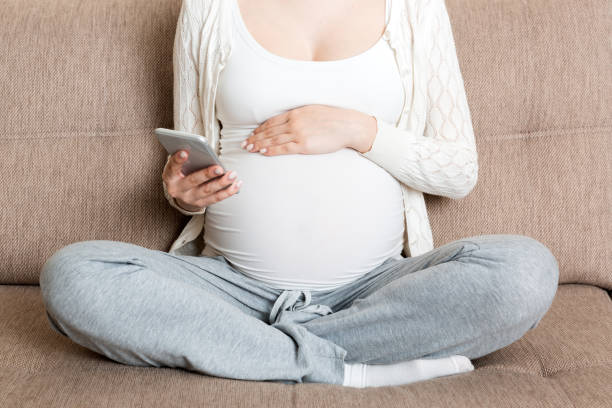 istock Caucasian pregnant girl using cellphone, resting on bed in home 1284590270