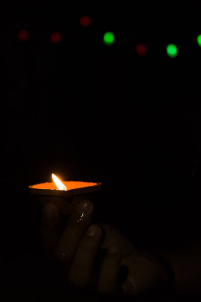 istock Diwali Diya (oil lamp) in hands with bokeh background. 1284592054