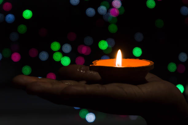 istock Diwali Diya (oil lamp) in hands with bokeh background. 1284593000
