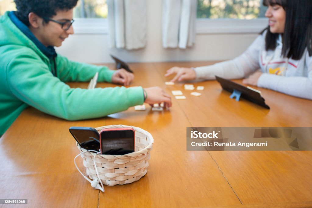 Teen friends at home. Digital detox concept. Teen friends playing games on the table at home without using the smartphone for a while. Digital detox concept. Digital Detox Stock Photo