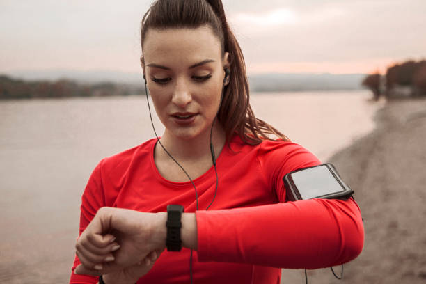 istock Young woman runner in sportswear uses a smart tracker on the beach 1284593157