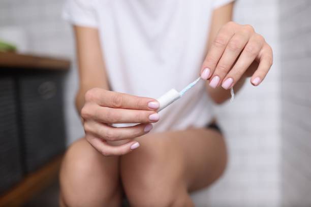 mulher sentada no banheiro e segurando absorvente higiênico nas mãos - tampon - fotografias e filmes do acervo