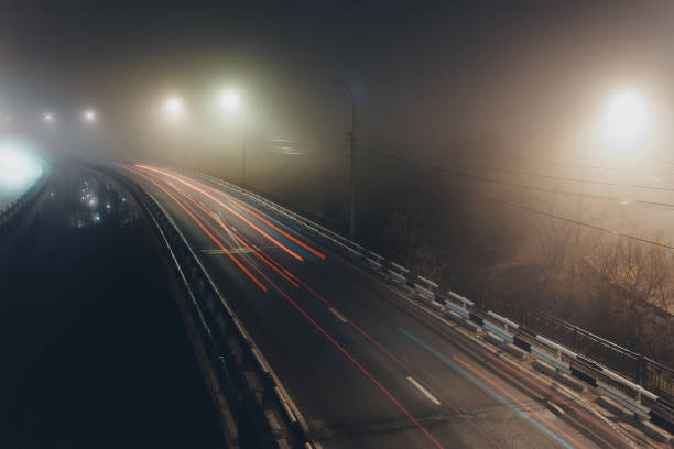 istock Foggy misty night road illuminated by street lights 1284594876