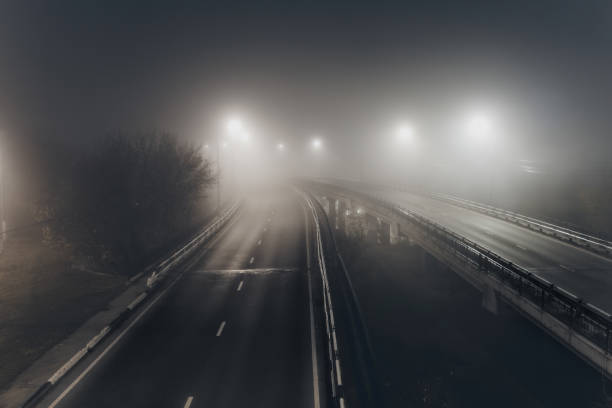 istock Foggy misty night road illuminated by street lights 1284595752