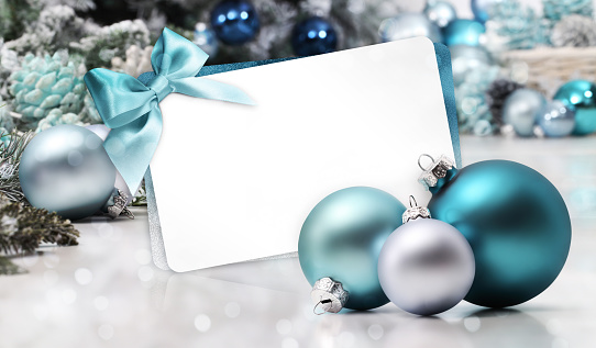 merry christmas gift card with bow and ribbon, next to blue Christmas balls, useful as a greeting card template with copy space