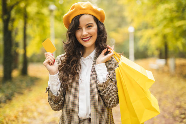 счастливая женщина моды проведения сумки и проведение кредитной карты - credit card paying boutique young women стоковые фото и изображения