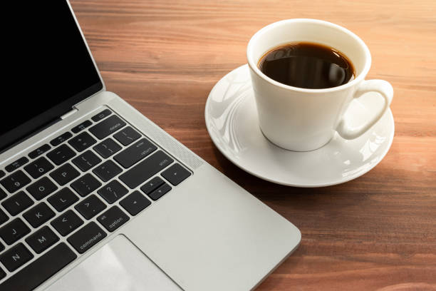 istock Laptop with cup of coffee on old wooden table. 1284599601