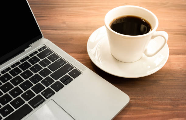 istock Laptop with cup of coffee on old wooden table. 1284599921