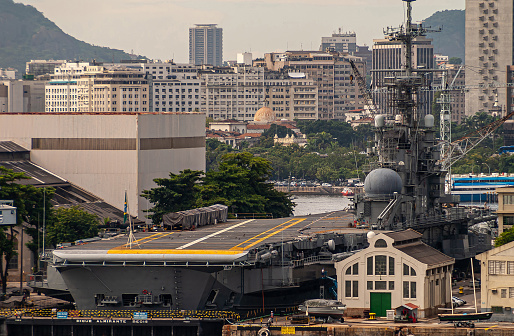 Rio de Janeiro, Brazil - December 22, 2008: Closeup of airplane carrier ship docked at Nave base with high rise buildings of El Centro district in back.