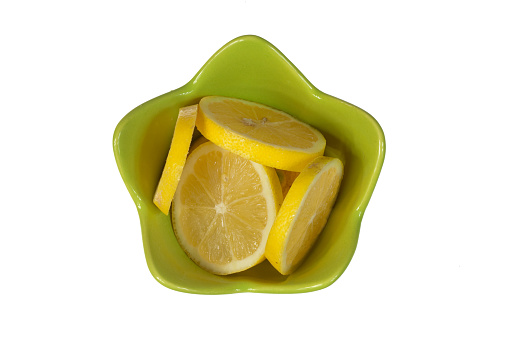 Isolated round slices of lemon in a green bowl directly above