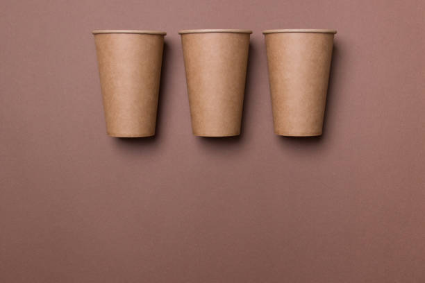 istock Three eco-friendly cardboard cups lie on a brown color paper background with copy space. Mock-up. Close-up. The concept of ecology 1284605159