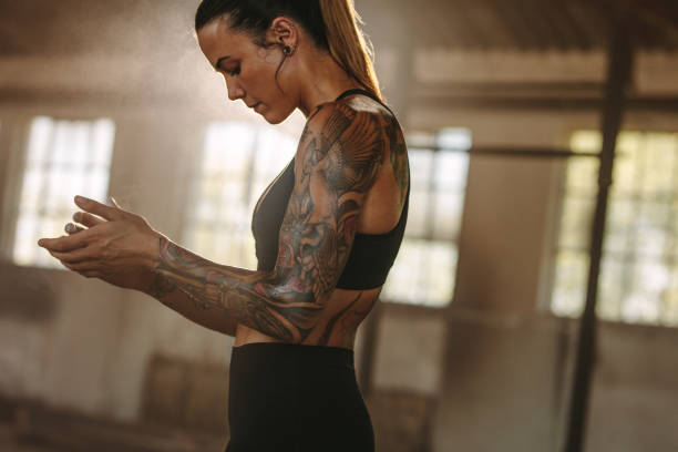 Fitness woman taking break after workout. Tattooed woman in sportswear resting after exercising at old warehouse.