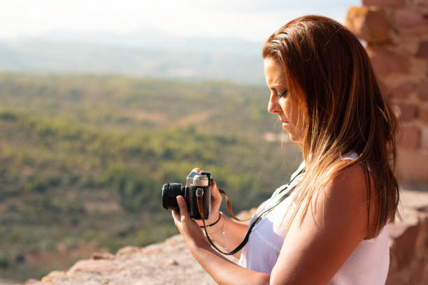 istock Woman holds an old camera learning how to use it in front of a landscape 1284608444