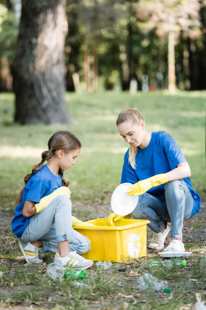 istock mother with daughter collecting plastic garbage in container with recycling symbol, ecology concept 1284608720