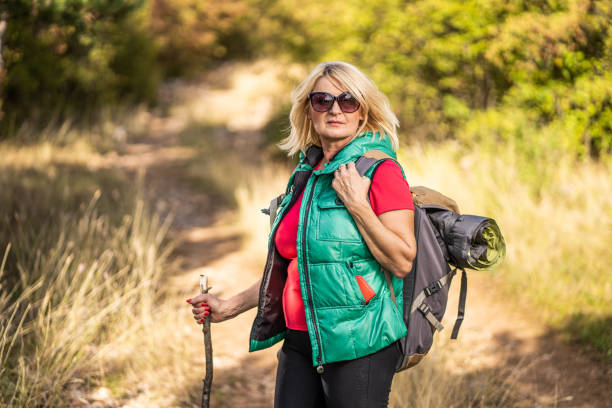 istock Senior woman with backpack hiking on sunny day 1284610287