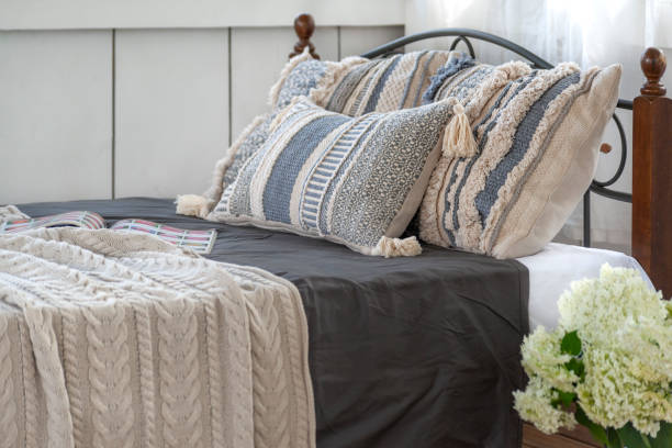 istock Handmade pillows on the bed. The bed is covered with a beige cable knit blanket 1284611451
