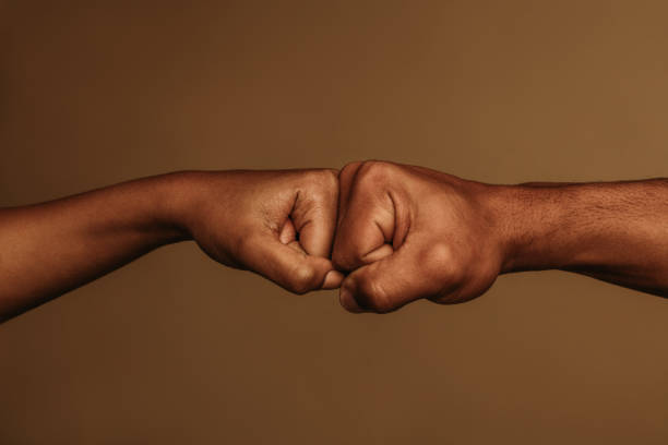 Close up of hands giving fist bump Cropped shot of two hands doing a fist bump. Two fists touching each other in opposite direction. racial equality photos stock pictures, royalty-free photos & images
