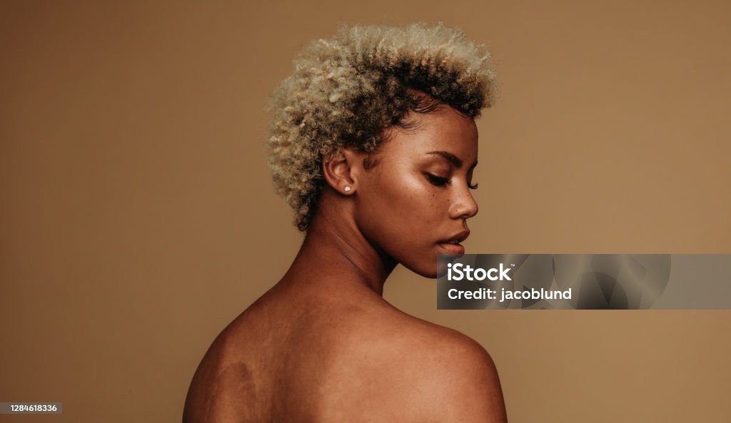 Side view portrait of african american woman Close up of african american woman looking over shoulder. Portrait of woman in curly hair on brown background. African-American Ethnicity Stock Photo