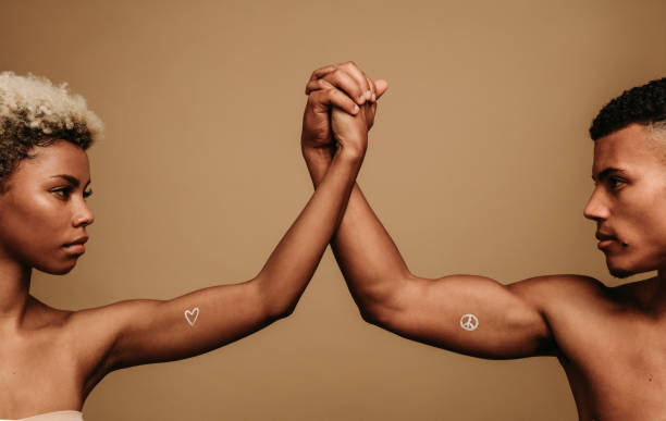 African american couple standing together holding hands in unity. Cropped shot of couple holding hands with symbols of protests painted on biceps.