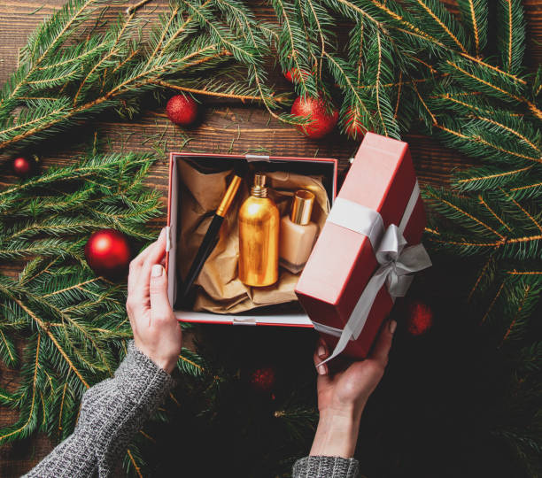 istock Female hands packaging cosmetics in a box next to Christmas decoration 1284619472