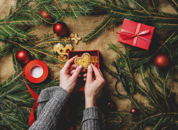 istock Female hands packaging cookies in a box next to Christmas decoration 1284619478