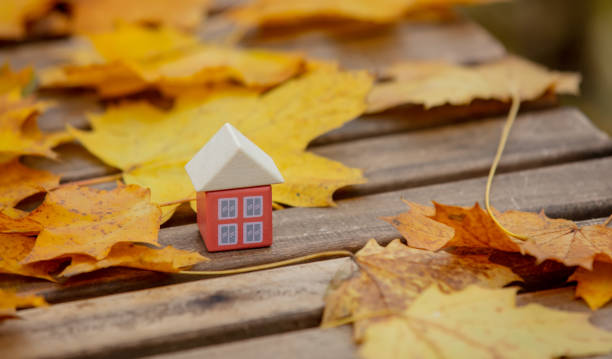 istock Little toy house next to autumn leaves on a table 1284621902