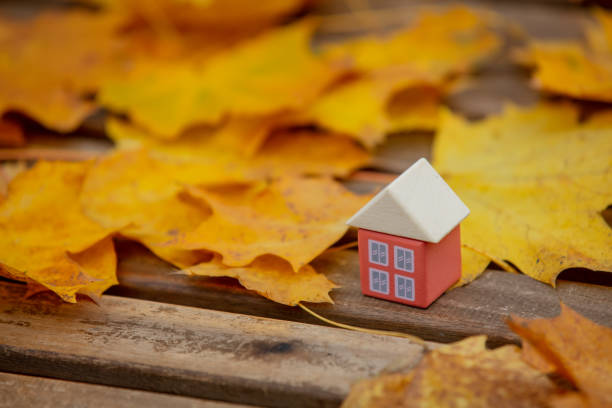 istock Little toy house next to autumn leaves on a table 1284621933