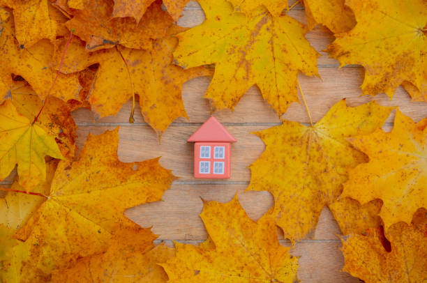 istock Little toy house next to autumn leaves on a table 1284621946