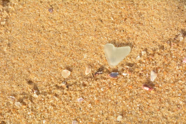 istock Glass heart in the sand beach 1284627614