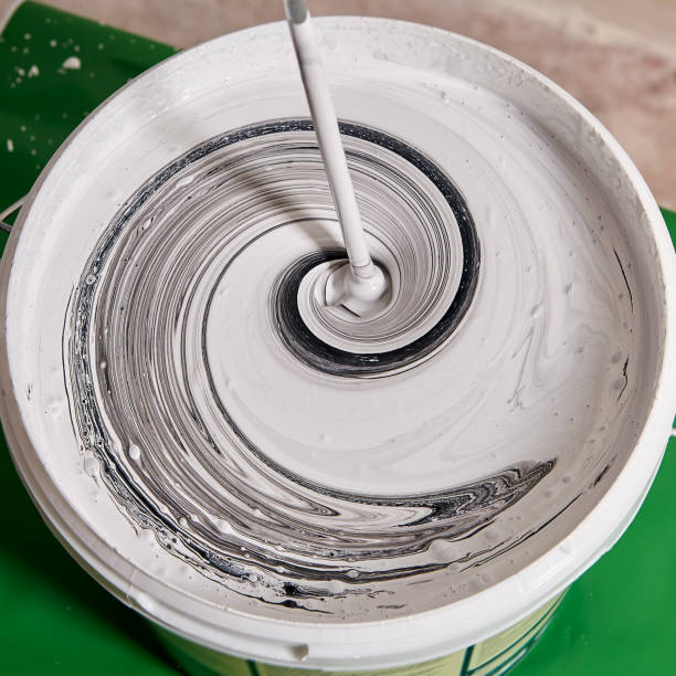 istock Painter is mixing paints for walls with paddle whisk in basket during renovation. 1284628805