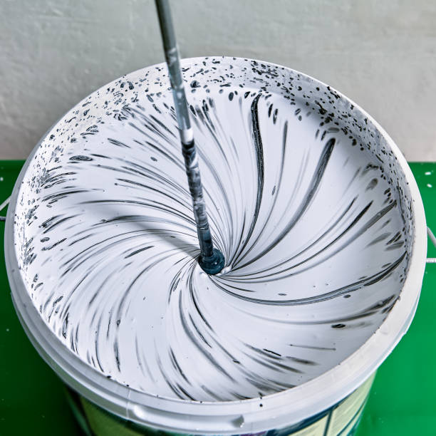 istock Painter combines paints for making color for painting walls with paddle whisk. 1284628814
