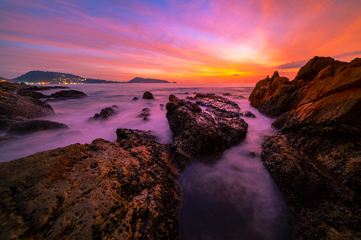 Long exposure image of Dramatic sky seascape with rocks in the foreground sunset or sunrise over sea scenery background