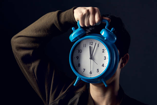 istock Young man isolated on a grey wall studio concept alarm clock 1284635908