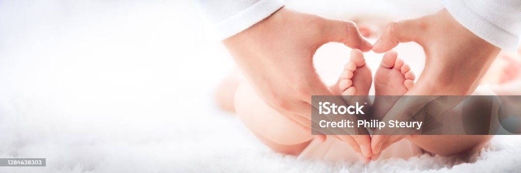 Baby's Feet In Heart Shaped Hands Mother Holding Baby's Feet In Heart Shaped Hands - Infant Care Concept Baby - Human Age Stock Photo