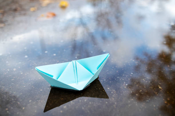 istock one blue paper ship floating on a water surface. outdoors. autumn season. greeting card with copy space. leadership conceptual. freedom concept 1284639914