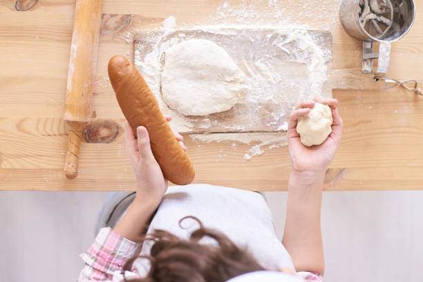 istock Wooden kitchen table. White flour. Preparation of test. Ready made pastry or bakery bread at home factory. Rolling bun. Young child chef baker 1284643096