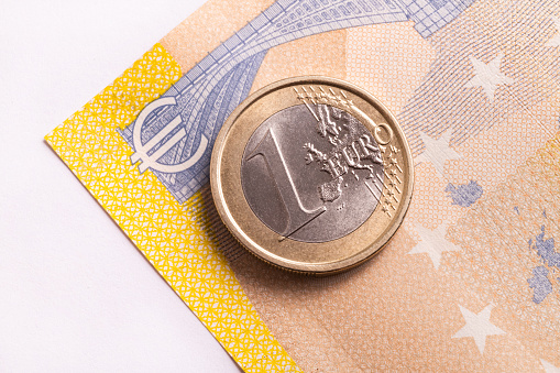 1 euro coin on the background of fragments of a 200 euro note and 
euro symbol