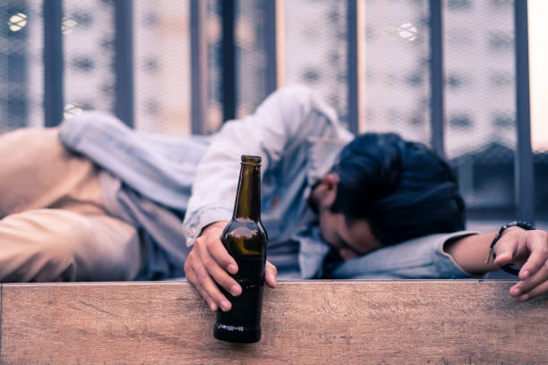 asian drunk man holding beer bottle lying on floor. young male adult crying having problem and feeling stress then drinking beer to forget those trouble and sleeping on ground. drunk unhealthy concept - drunk imagens e fotografias de stock