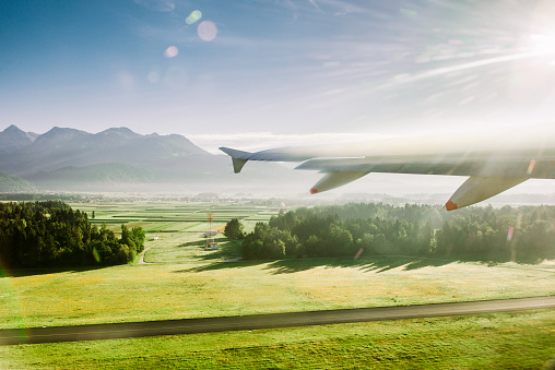 Wing of an airplane flying over land in the sun