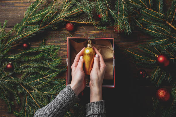 Female hands packaging cosmetics in a box next to Christmas decoration