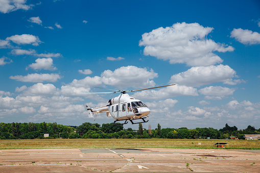 A white helicopter takes off from the runway.
