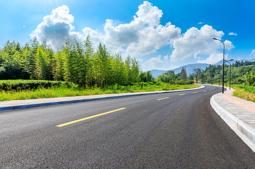 Countryside asphalt road and green plants with mountain natural scenery in Hangzhou on a sunny day.