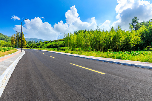 Asphalt road and green plants with mountain natural scenery in Hangzhou on a sunny day.