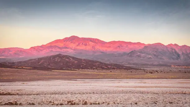 Colorful Panorama of Death Valley Salt Basin Desert in atmospheric moody pink sunset twlight. Death Valley's Badwater Basin is the Point of the lowest elevation in North America at 282f - 86m below sea level. Death Valley National Park, Eastern California, USA, North America