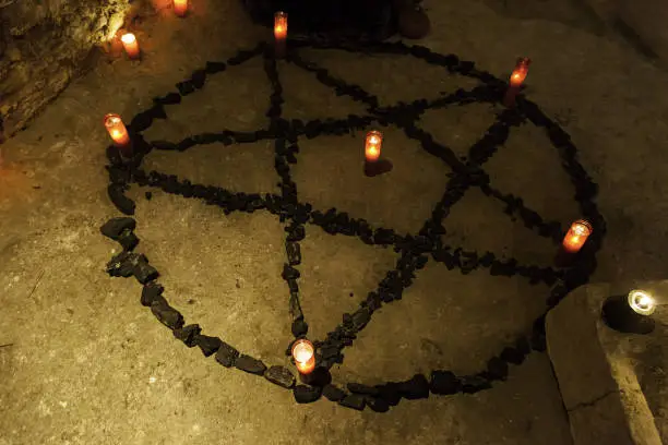 Pentacle satanic with candles in a dark ritual, detail of black magic and beliefs