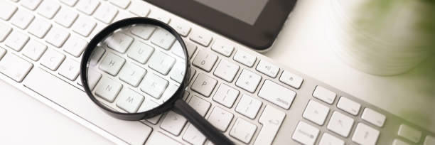 Online business analysis Close-up of magnifier for enlargement lying on white computer keyboard. Workplace interior. Modern tablet on desk in office. Business and company concept wide screen photos stock pictures, royalty-free photos & images