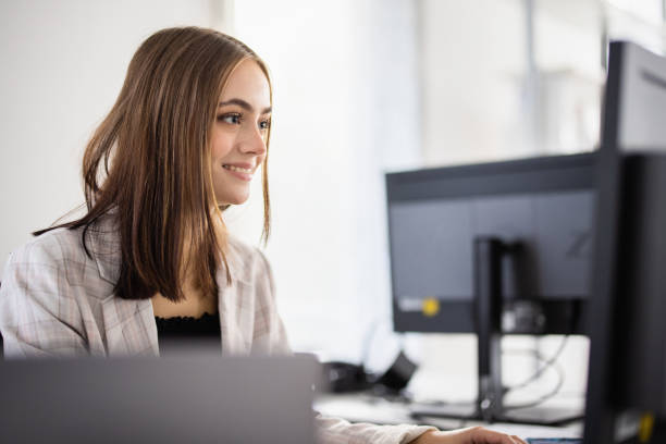 istock Young woman working in modern office at computer desk 1284672454