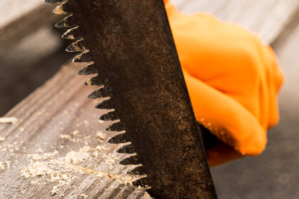 istock A hand in an orange glove is sawing a board with an old rusty hand saw. 1284673825